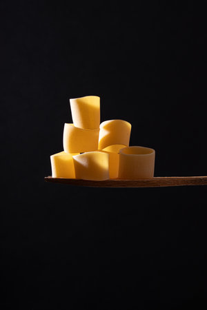 several dry pastry pieces on spoon, black background, food concept