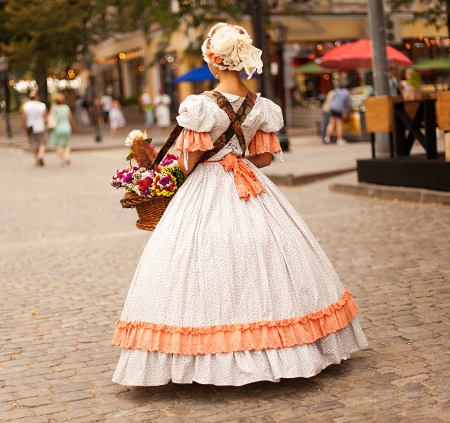 medieval women from back with flowers in hands on a modern street の写真素材