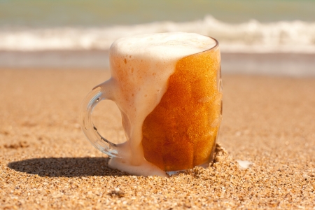 Glass of cold beer on the sea beachの写真素材