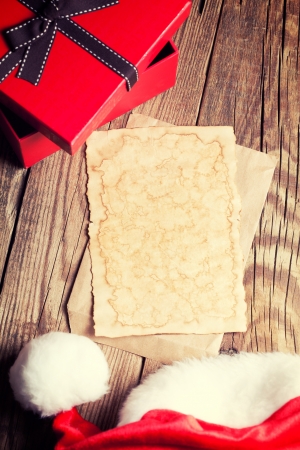 sheet of vintage paper with gift box and santa's hat on wooden backgroundの写真素材