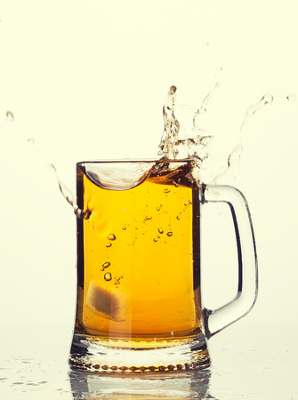 Mug of beer with splash and foamの写真素材