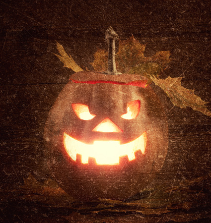 jack-o-lantern with leaves on wooden table の写真素材
