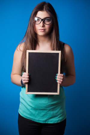 beautiful young woman holding blackboard on blue backgroundの写真素材
