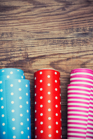 Rolls of colored wrapping paper on wooden background の写真素材