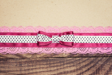 vintage background with wood, old paper and pink and white polka dot ribbon with bowの写真素材