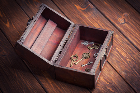 vintage keys inside old treasure chest on wooden background