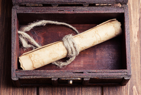 old paper roll inside treasure chest on wooden backgroundの写真素材