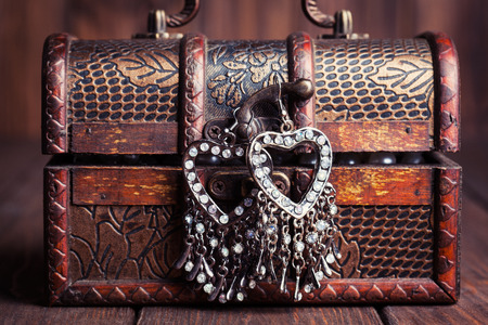vintage earrings in a form of hearts hanging on old treasure chestの写真素材