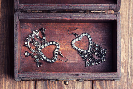 vintage earrings in a form of hearts inside old treasure chestの写真素材