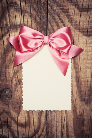 blank paper sheet with pink bow on wooden backgroundの写真素材