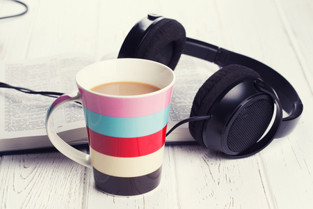 cup of coffee with headphones on wooden backgroundの写真素材