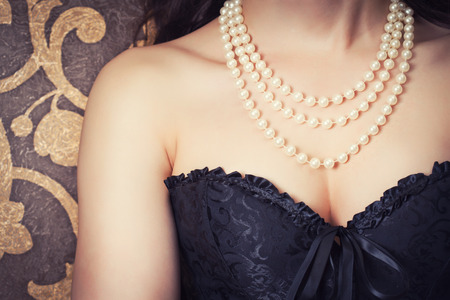 woman wearing black corset and pearls against retro backgroundの写真素材