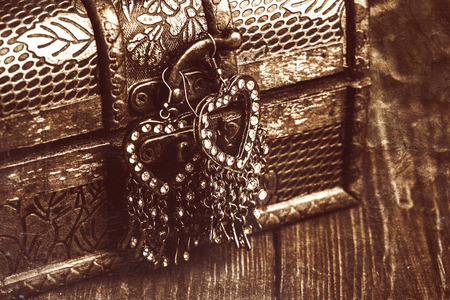 vintage earrings in a form of hearts hanging on old treasure chestの写真素材