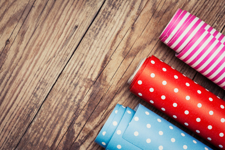 Rolls of colored wrapping paper on wooden background の写真素材