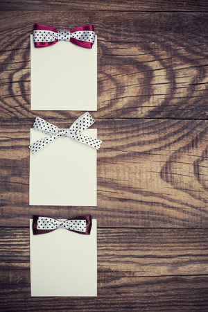 three blank paper sheets with colorful bows on wooden backgroundの写真素材