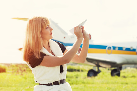 beautiful woman holding paper plane against real planeの写真素材