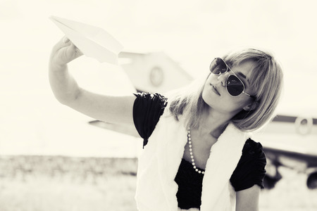 beautiful woman holding paper plane against real plane