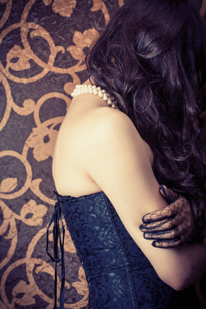 woman wearing black corset and pearls against retro backgroundの写真素材