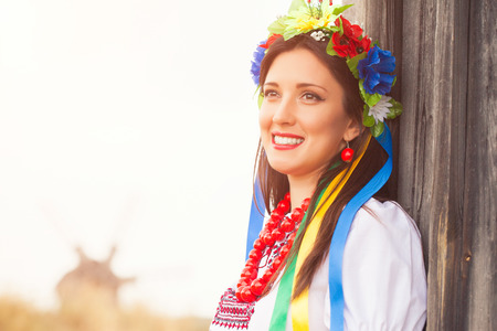 beautiful young woman wearing national ukrainian clothes posing outdoorsの写真素材