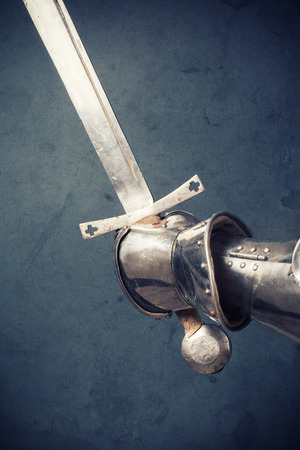 closeup of knight's hand in armor gloves holding two-handed swordの写真素材