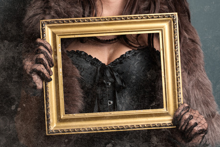 woman wearing corset and fur and holding vintage golden frameの写真素材