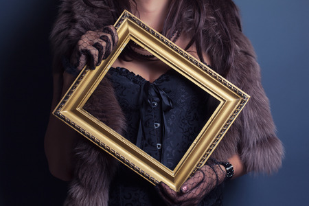 woman wearing corset and fur and holding vintage golden frameの写真素材