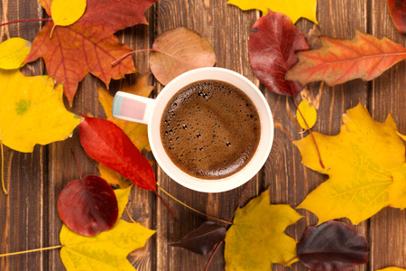 coffee cup on the autumn fall leaves on wooden backgroundの写真素材