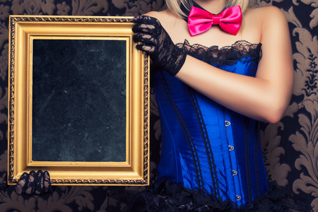 beautiful cabaret woman posing with golden frame against retro wallpapersの写真素材