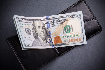 purse with hundred dollar banknotes on grey background