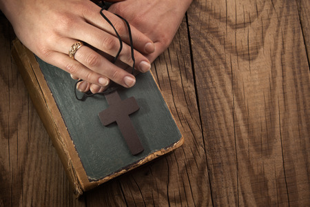 closeup of hands holding vintage cross on Bibleの写真素材