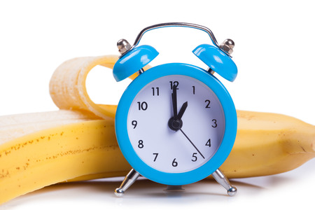 Alarm clock and banana on white backgroundの写真素材