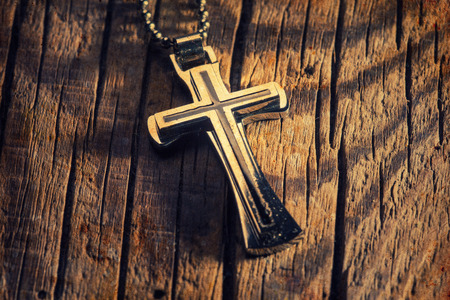 Silver cross on a wood background close up imageの写真素材