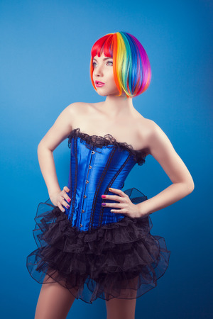 beautiful woman wearing colorful wig against blue backgroundの写真素材