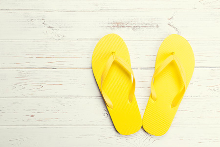 Yellow flip-flops on a white wooden backgroundの写真素材