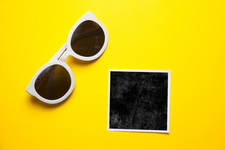 Stylish white sunglasses on yellow background with white paper frames