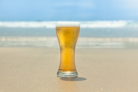 glass of beer with sea and clouds backgroundの写真素材