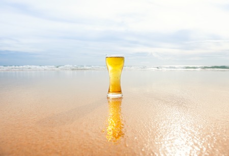 glass of beer with sea and clouds backgroundの写真素材