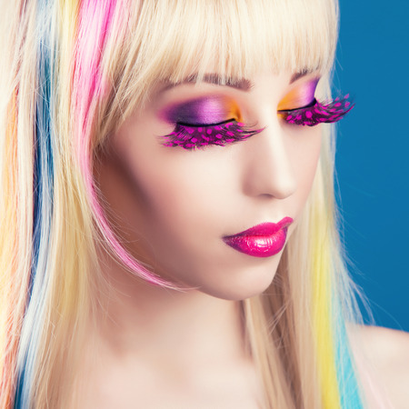 beautiful young woman with blonde hair against blue backgroundの写真素材