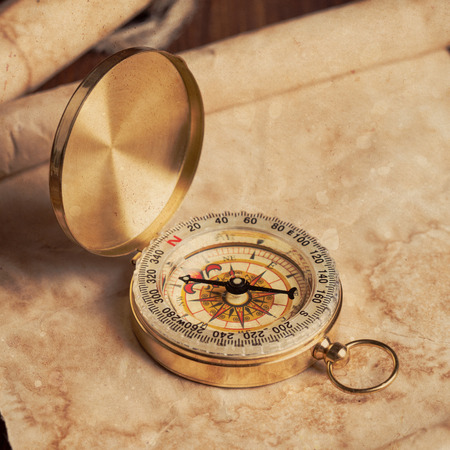 old unrolled map, rolled map and compass on wooden tableの写真素材