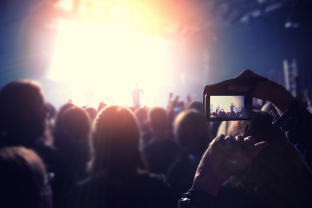 Silhouettes of people and musicians in big concert stage. Bright beautiful rays of lightの写真素材
