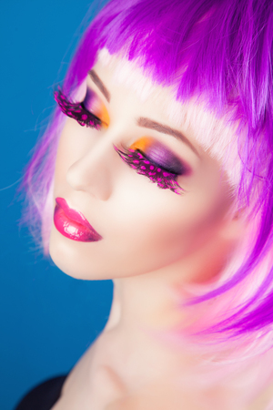 beautiful woman wearing colorful wig against blue backgroundの写真素材