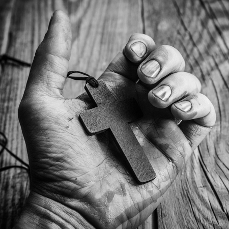 Cross in hand on wooden backgroundの写真素材