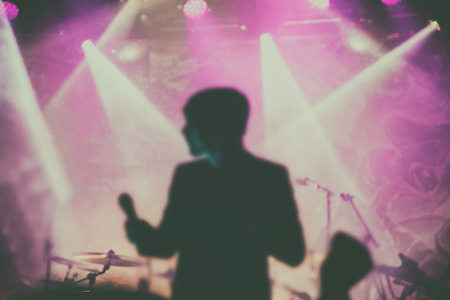 Silhouettes of people and musicians in big concert stage. Bright beautiful rays of lightの写真素材