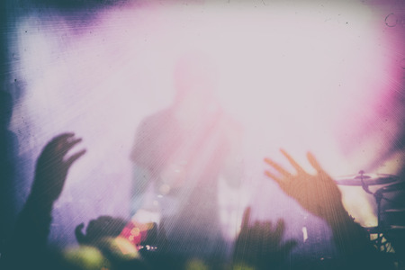 Silhouettes of people and musicians in big concert stage. Bright beautiful rays of lightの写真素材