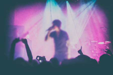 Silhouettes of people and musicians in big concert stage. Bright beautiful rays of lightの写真素材