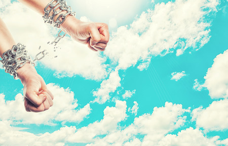 Two hands in chains on a heavens background with a flashの写真素材