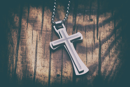 Silver cross on a wood background close up imageの写真素材
