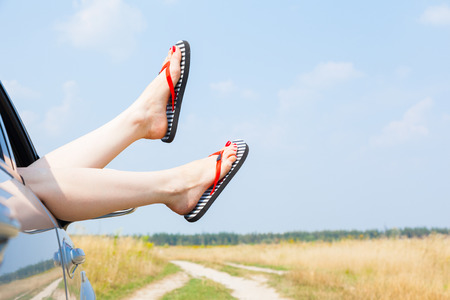 female legs dangling from the open car window in the shalesの写真素材