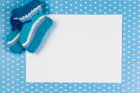 knitted baby socks and blank note on blue polka dot backgroundの写真素材