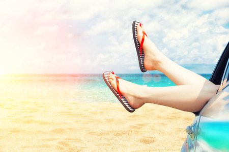 female legs dangling from the open car window in the shalesの写真素材